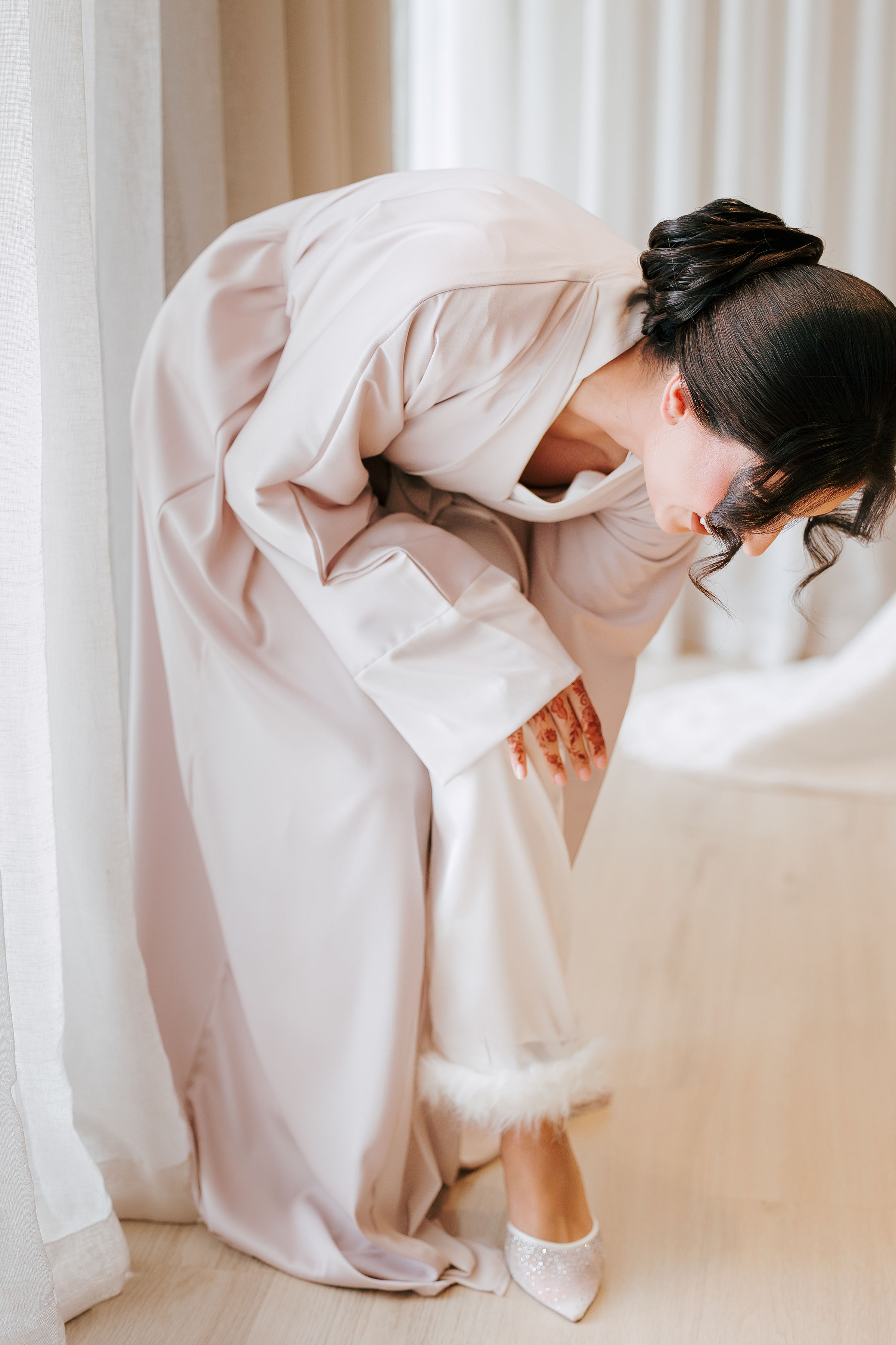 Bride in a soft robe getting ready on the morning of her wedding